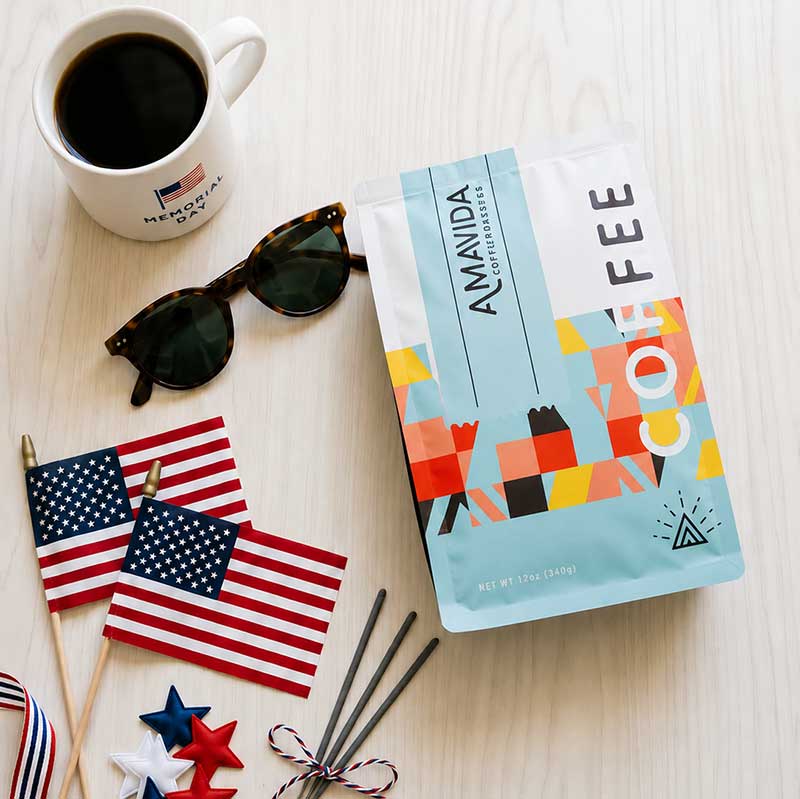 12 oz bag of Amavida Coffee Roasters organic coffee flat lay with sunglasses and American flags